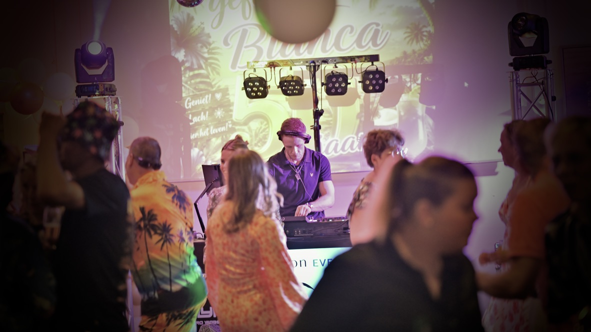 DJ Tonicity draait voor een feestend publiek onder warme podiumlichten.